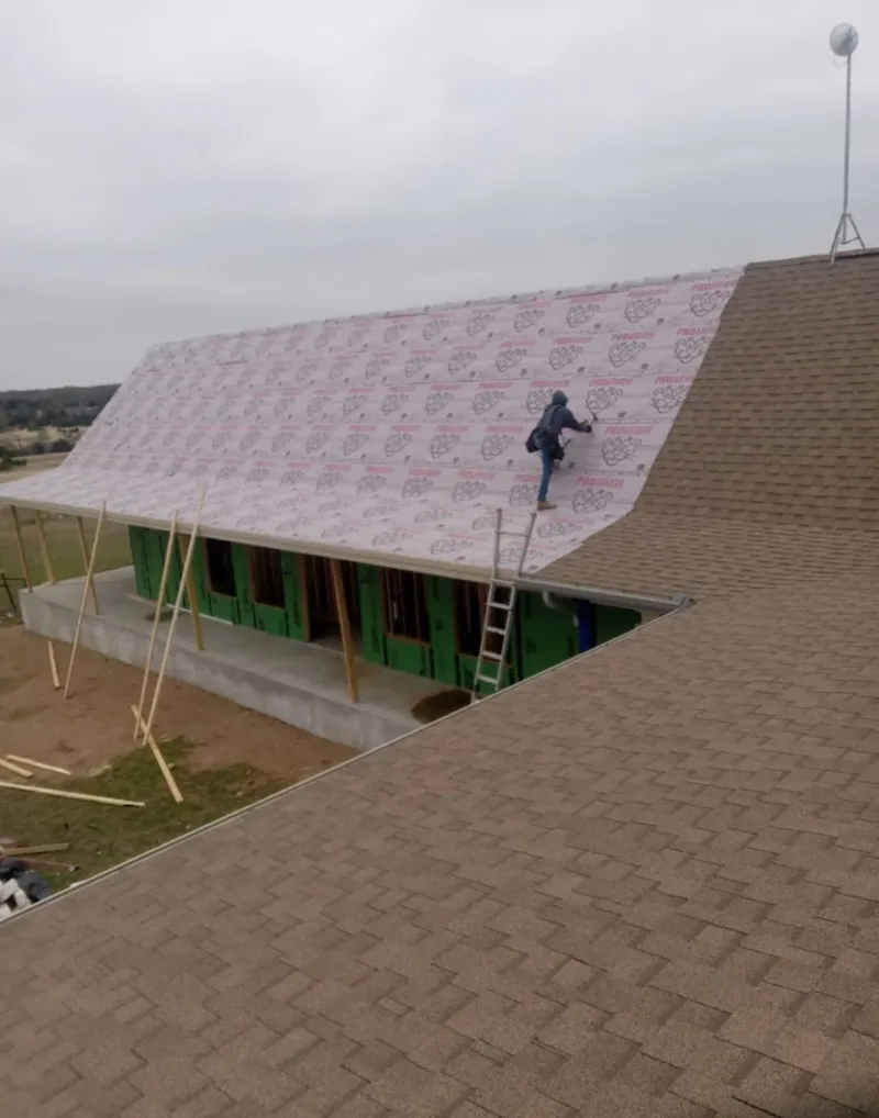 Worker preparing underlayment for a metal roof installation in Granger